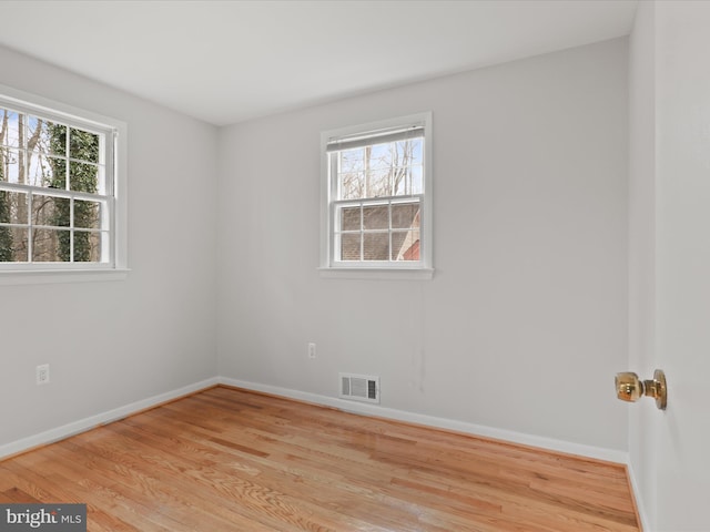 unfurnished room with light wood-type flooring, a healthy amount of sunlight, visible vents, and baseboards