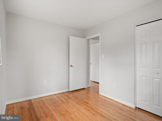 unfurnished bedroom featuring light wood finished floors, a closet, and baseboards