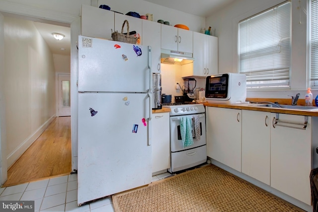 kitchen featuring white appliances, white cabinetry, light tile patterned floors, and sink