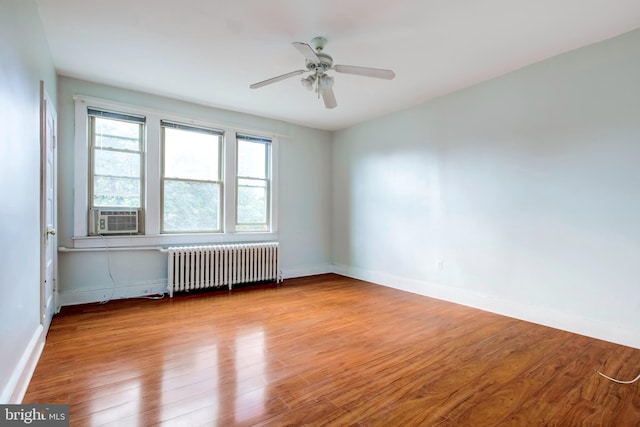 empty room with light hardwood / wood-style flooring, radiator heating unit, cooling unit, and ceiling fan