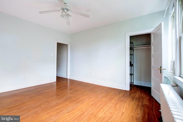 unfurnished bedroom with radiator, wood-type flooring, a closet, and ceiling fan