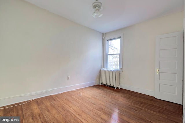 spare room with hardwood / wood-style floors and radiator heating unit