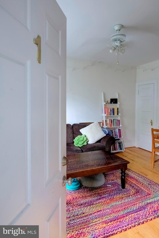 living area featuring wood-type flooring and ceiling fan