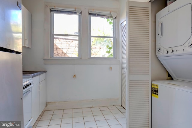 clothes washing area featuring stacked washer / drying machine and light tile patterned floors