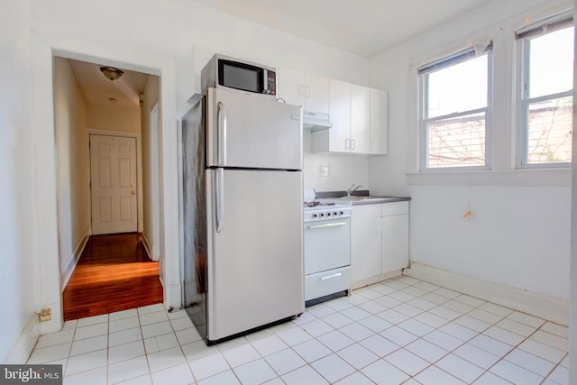 kitchen featuring white appliances, light tile patterned flooring, sink, and white cabinets