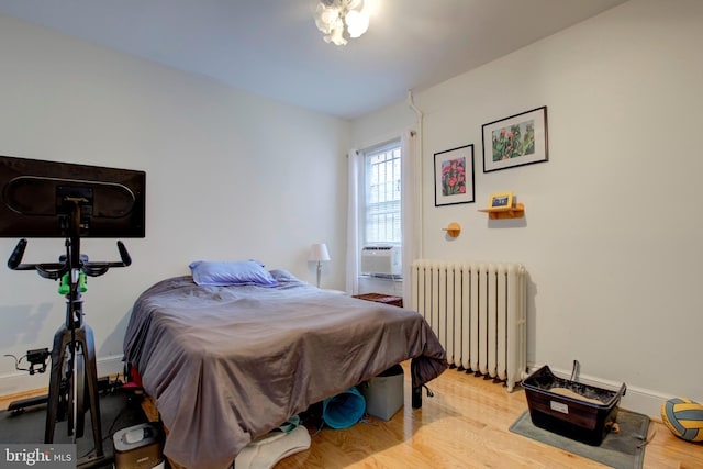 bedroom with light hardwood / wood-style flooring, cooling unit, and radiator heating unit