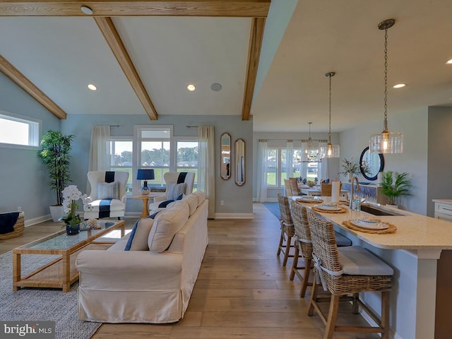 living room with light wood-type flooring, plenty of natural light, sink, and vaulted ceiling with beams