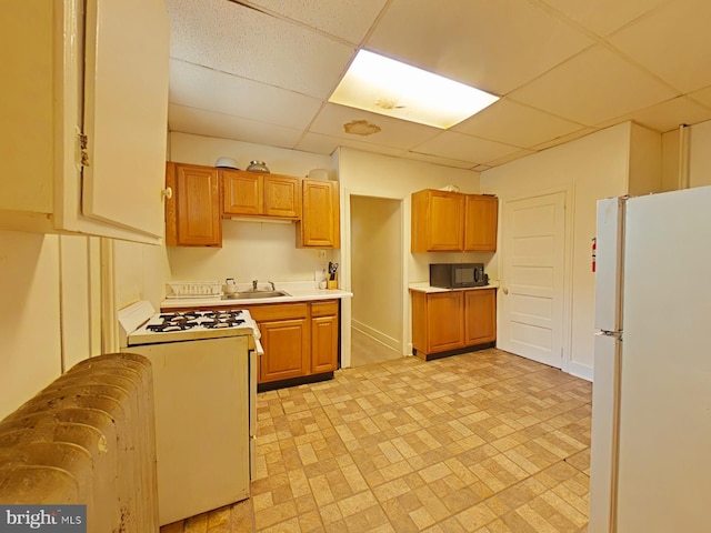 kitchen featuring white appliances, sink, and a drop ceiling