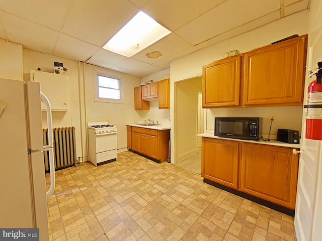 kitchen with radiator, a paneled ceiling, white appliances, and sink