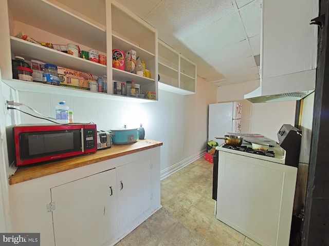 kitchen with wooden counters, white cabinetry, white appliances, and washer / dryer