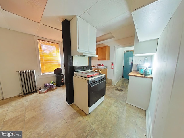 kitchen with white gas range, white cabinetry, and radiator heating unit