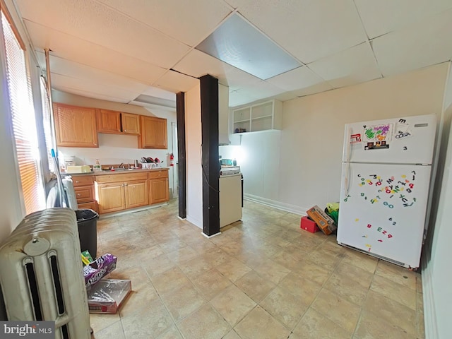 kitchen with a paneled ceiling, sink, white fridge, and light tile patterned floors