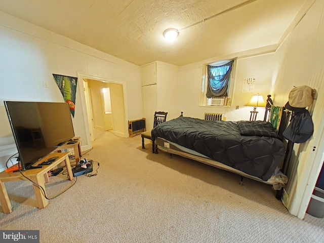 carpeted bedroom with a textured ceiling, radiator heating unit, and heating unit