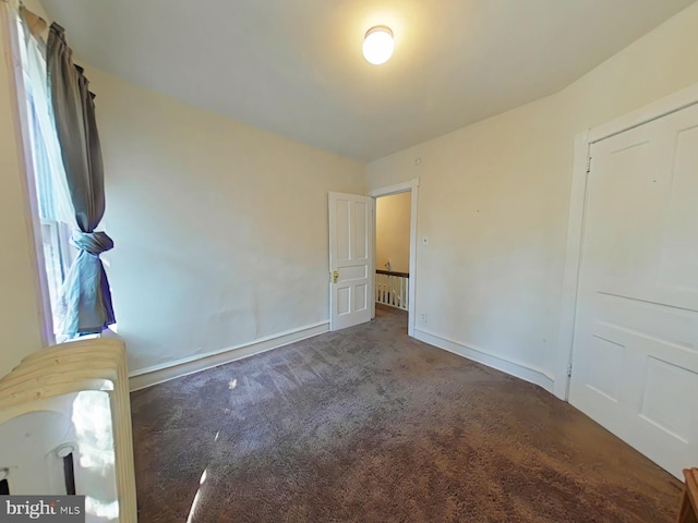 unfurnished bedroom with a closet and dark carpet