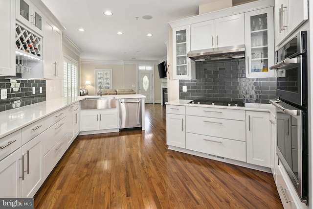 kitchen with appliances with stainless steel finishes, tasteful backsplash, white cabinetry, sink, and kitchen peninsula