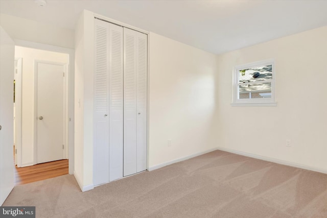 unfurnished bedroom featuring light carpet and a closet