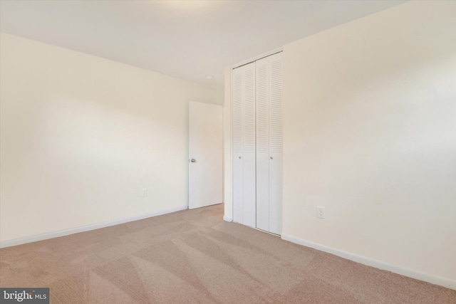 unfurnished bedroom with light carpet and a closet