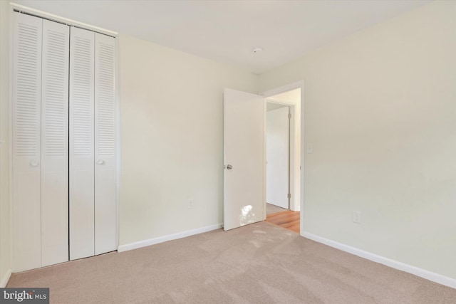 unfurnished bedroom featuring light carpet and a closet