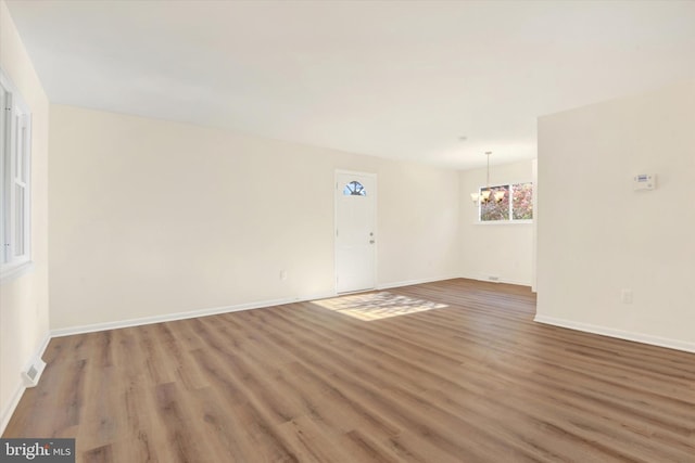 spare room with dark hardwood / wood-style flooring and a notable chandelier