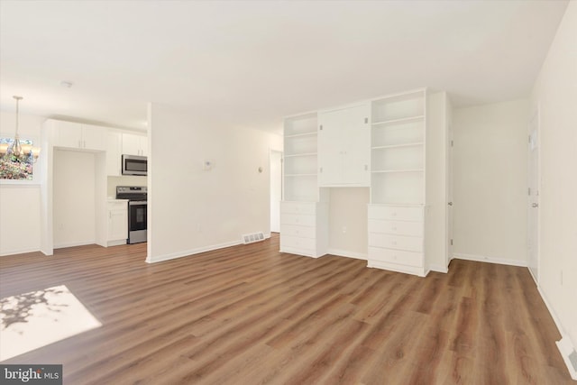 unfurnished living room with hardwood / wood-style flooring and an inviting chandelier