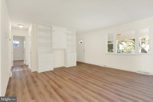 unfurnished living room featuring wood-type flooring and a wealth of natural light