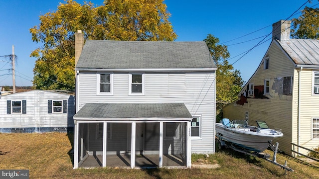 rear view of house featuring a patio, a lawn, and a sunroom