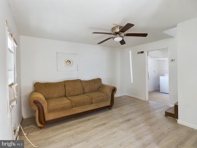 living room featuring light hardwood / wood-style flooring, washer / clothes dryer, and ceiling fan