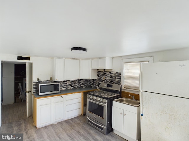 kitchen featuring stainless steel appliances, sink, light wood-type flooring, and white cabinets