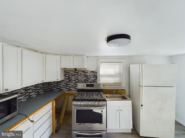 kitchen featuring appliances with stainless steel finishes, sink, backsplash, hardwood / wood-style floors, and white cabinets