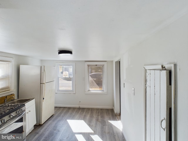 kitchen featuring sink, gas stove, white cabinetry, white fridge, and light hardwood / wood-style flooring