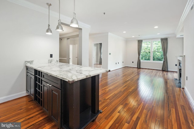 kitchen with kitchen peninsula, ornamental molding, dark wood-type flooring, dark brown cabinetry, and light stone counters