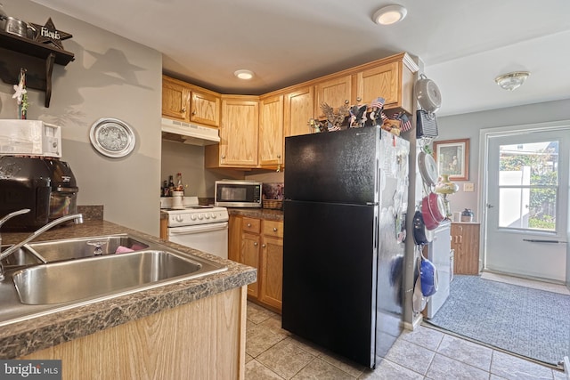 kitchen with light brown cabinets, light tile patterned floors, black fridge, white stove, and sink