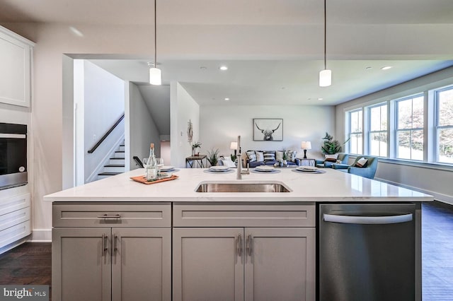 kitchen featuring dark wood-type flooring, stainless steel appliances, sink, and pendant lighting