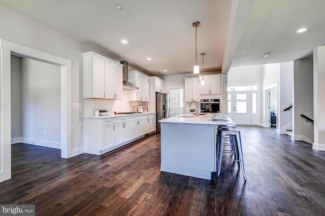 kitchen featuring appliances with stainless steel finishes, white cabinetry, a kitchen island with sink, and dark hardwood / wood-style floors