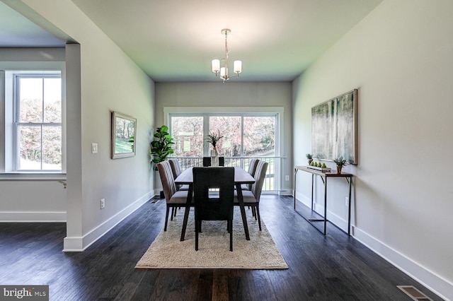 dining space featuring dark wood-type flooring, a notable chandelier, and plenty of natural light