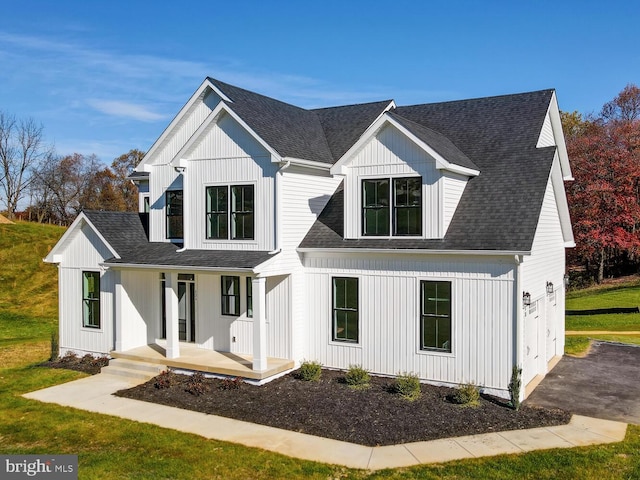 modern farmhouse featuring covered porch, a garage, and a front yard