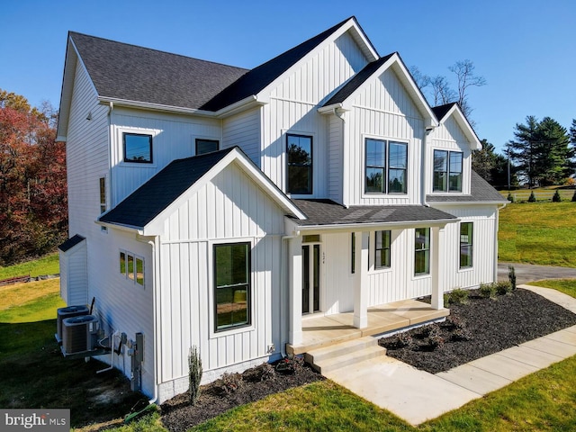 rear view of house with cooling unit, covered porch, and a lawn