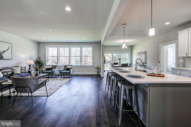 kitchen featuring sink, an island with sink, white cabinetry, pendant lighting, and dark hardwood / wood-style floors