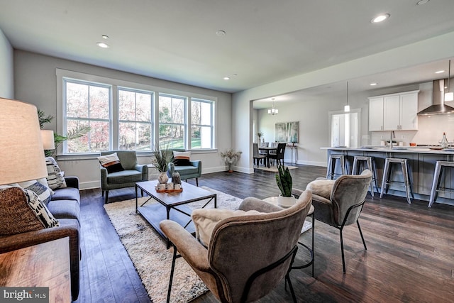 living room with a notable chandelier, sink, and dark hardwood / wood-style flooring