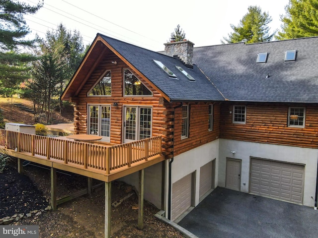 rear view of property featuring a wooden deck and a garage