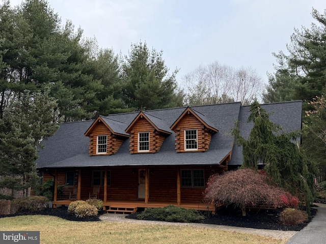 log-style house featuring a porch and a front lawn