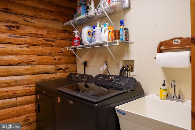 clothes washing area featuring washing machine and clothes dryer, wooden walls, and sink