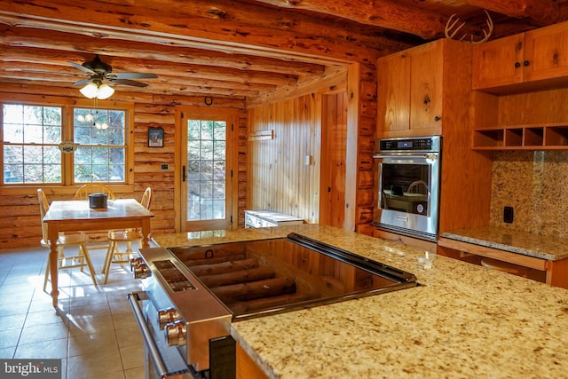 kitchen featuring ceiling fan, light stone countertops, log walls, light tile patterned flooring, and appliances with stainless steel finishes