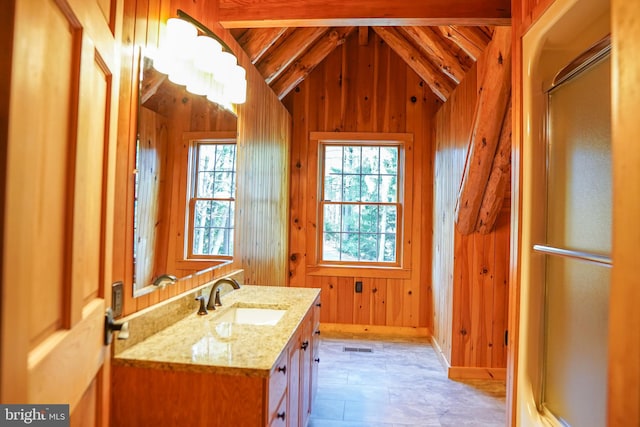 bathroom featuring vanity, lofted ceiling with beams, a shower with shower door, and wood walls