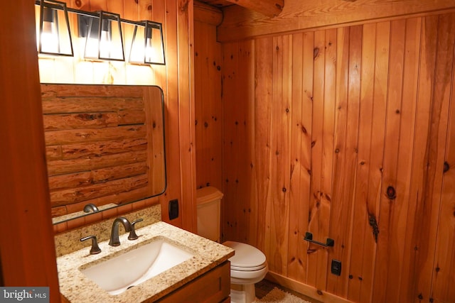 bathroom featuring vanity, toilet, and wooden walls