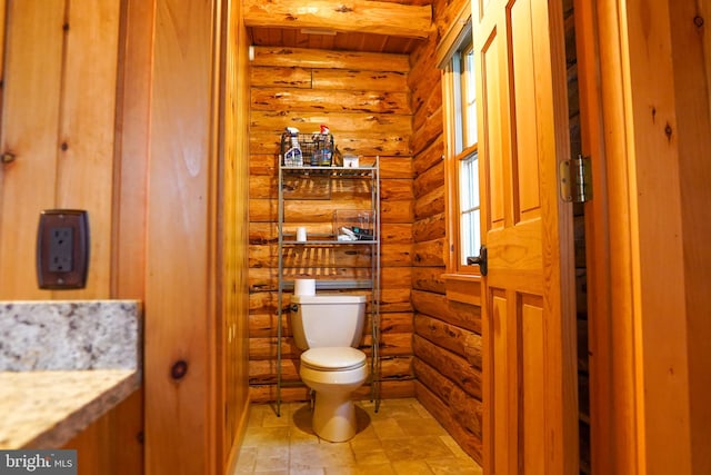 bathroom with log walls, vanity, toilet, and beamed ceiling