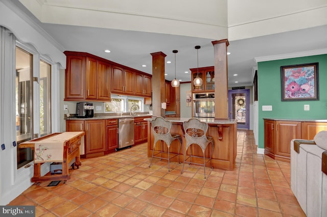 kitchen with ornate columns, stainless steel appliances, ornamental molding, and pendant lighting