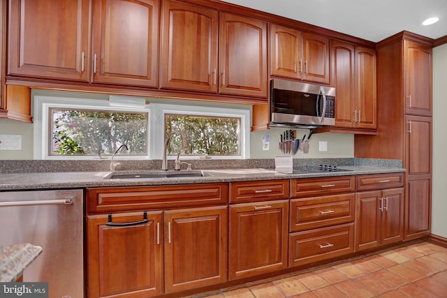 kitchen with light tile patterned floors, stainless steel appliances, stone countertops, and sink