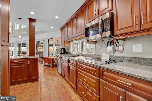 kitchen with appliances with stainless steel finishes, sink, light stone counters, ornamental molding, and light tile patterned floors