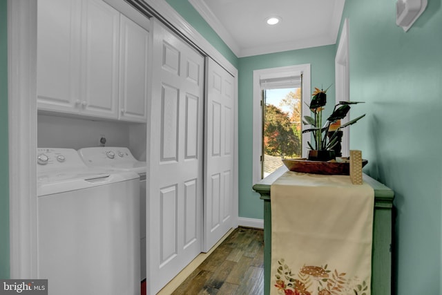 clothes washing area featuring dark wood-type flooring, crown molding, cabinets, and washer and clothes dryer